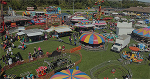Aerial view of a colorful fairground with various rides, booths, and attractions